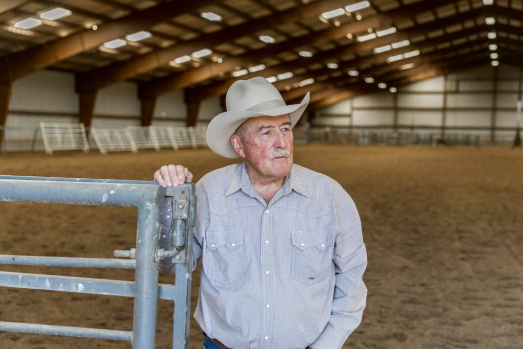man in cowboy hat stands in front of indoor arena