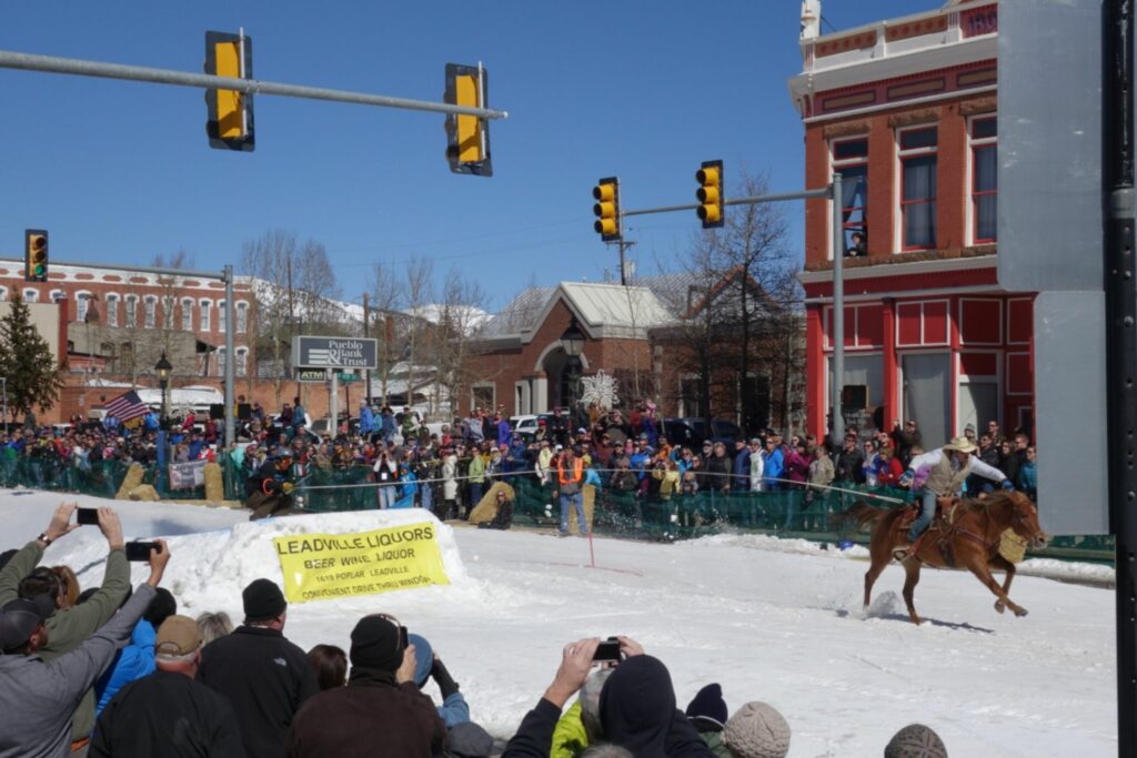 horse pulls skier through downtown Leadville street in skijoring competition