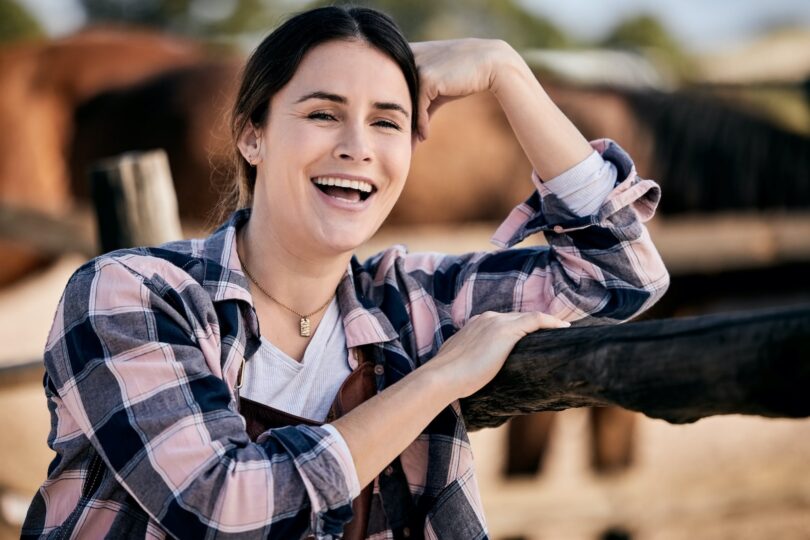 girl laughing with horses behind her