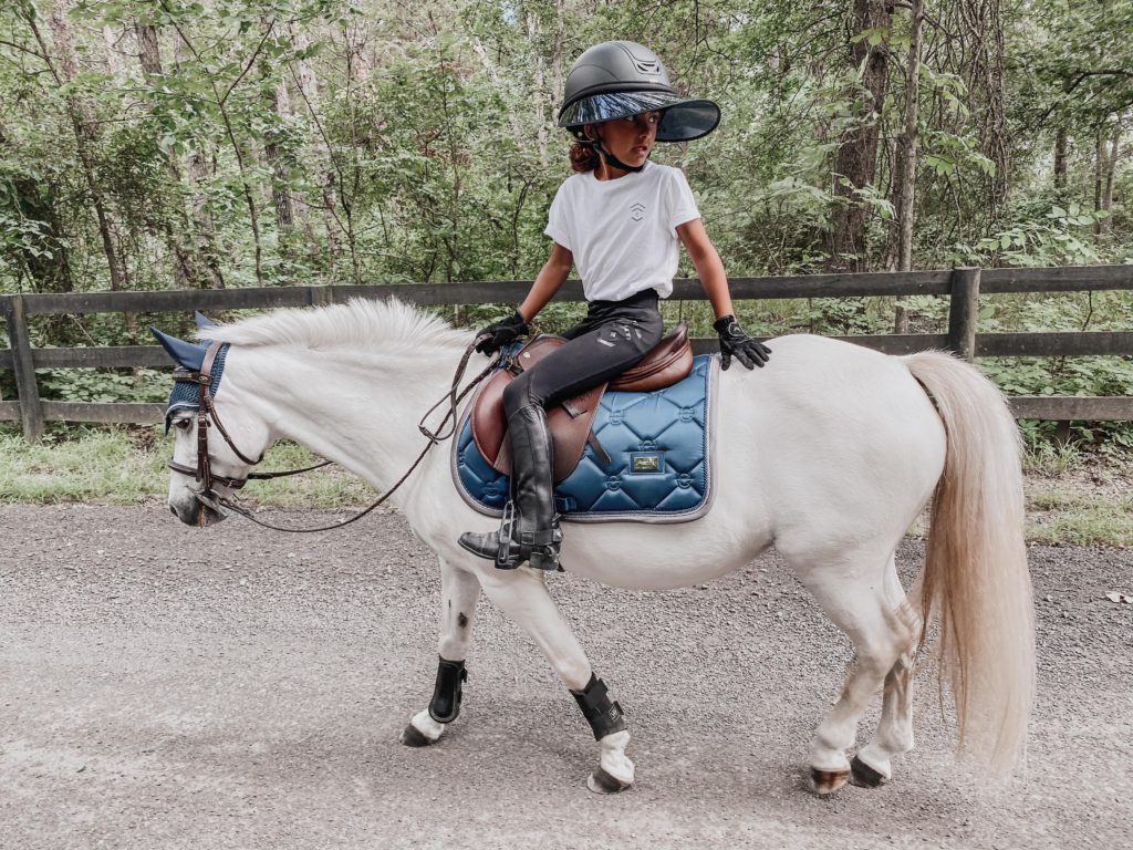 girl walking pony down road