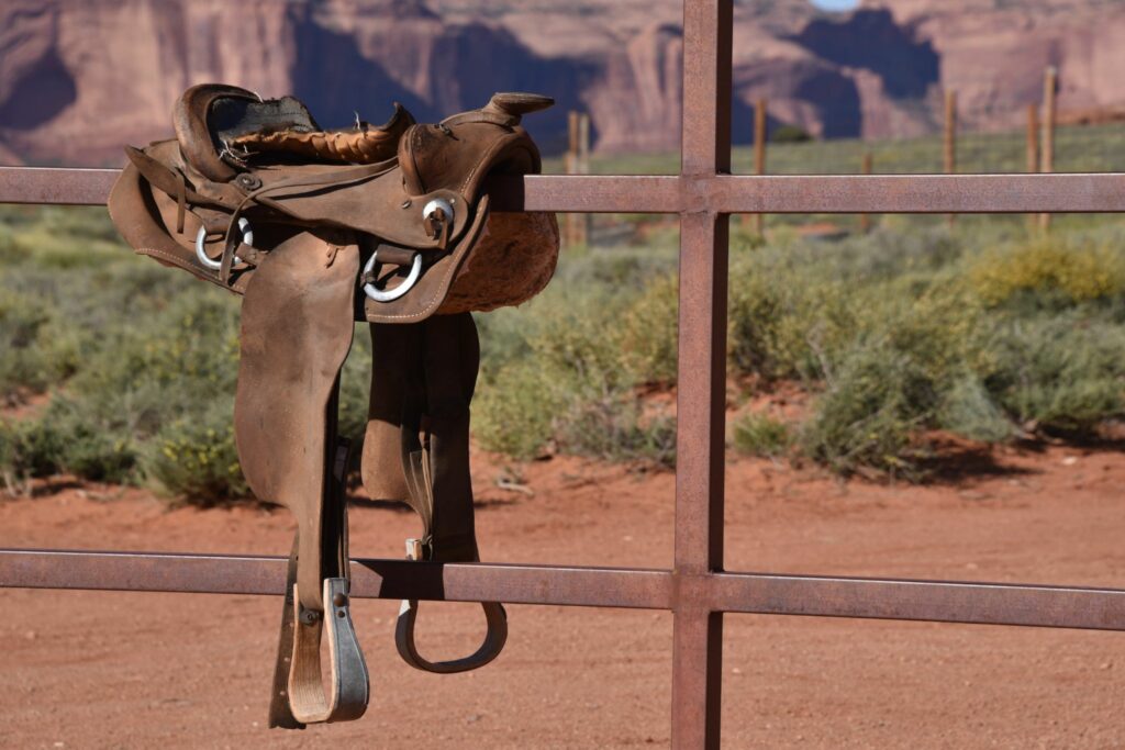 western saddle on metal fence mountain background