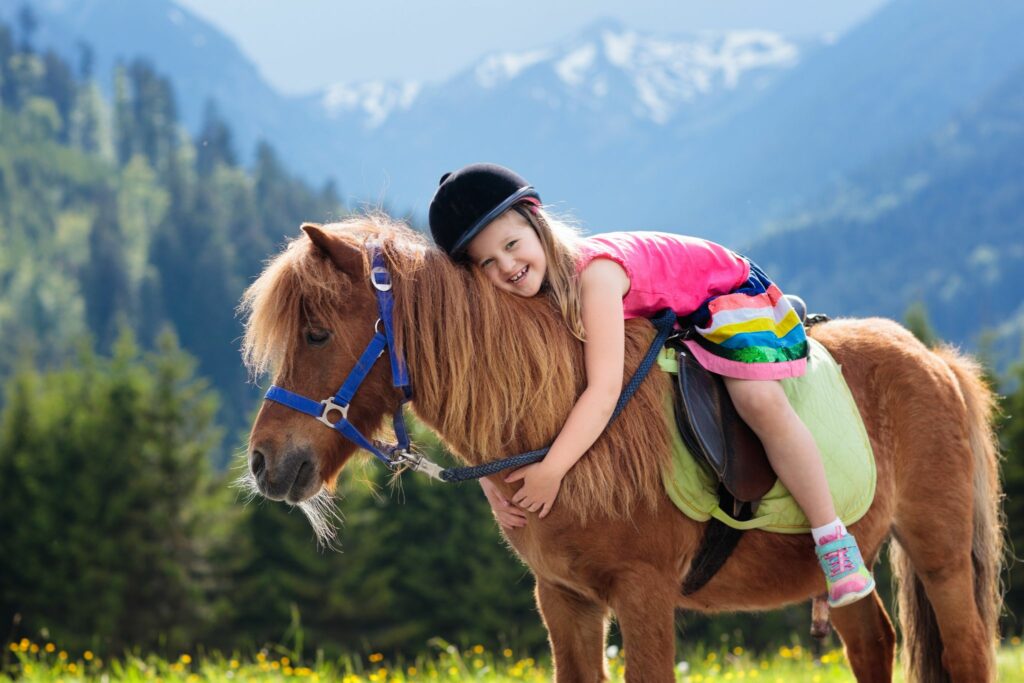 girl hugging pony with mountain backdrop