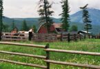 wood horse fencing with red barn in background