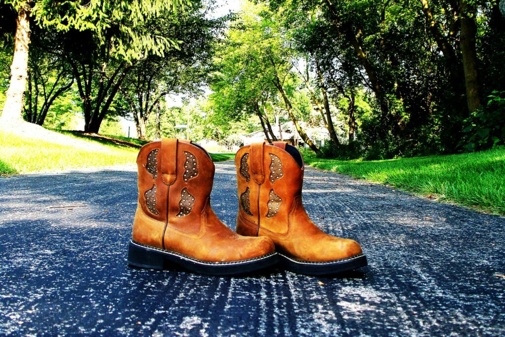 brown short cowboy boots on asphalt with green background