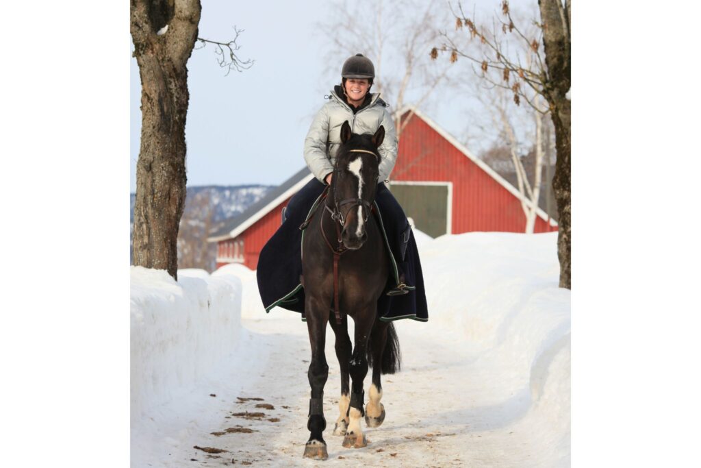girl riding horse with half sheet in winter snow