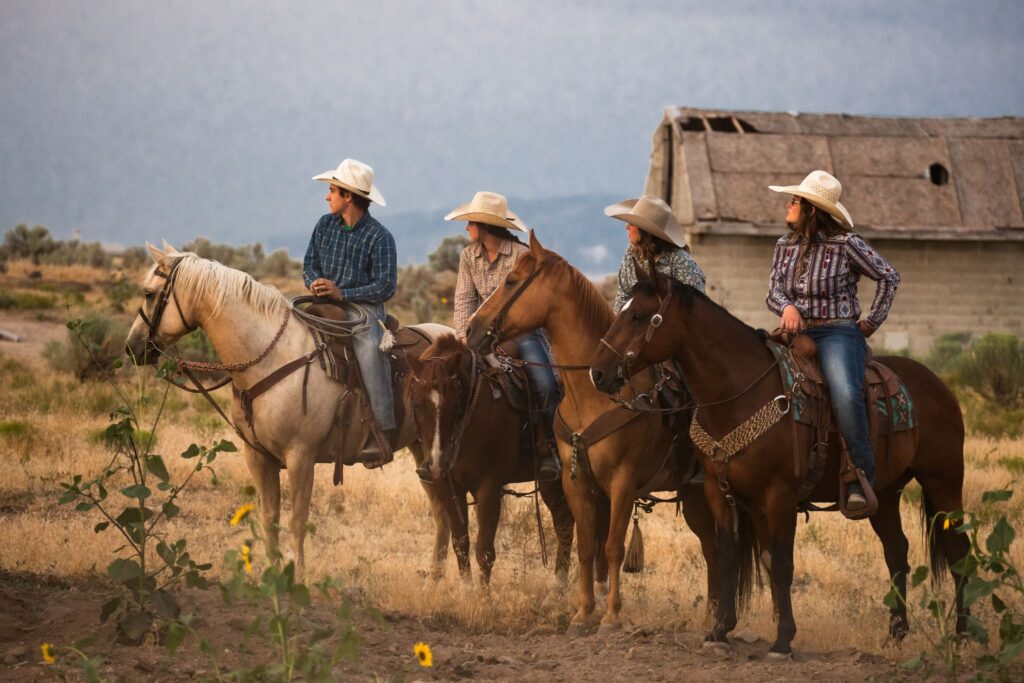 four people riding horses wearing cowboy hats