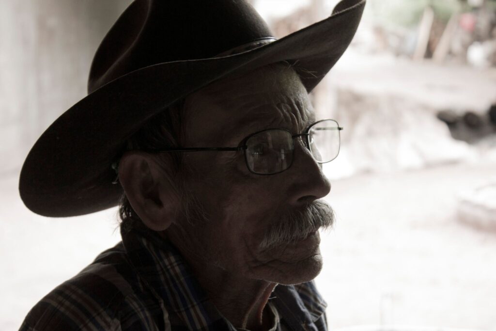 man wearing glasses and cowboy hat black and white
