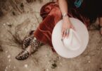 light colored cowboy hat held by woman wearing cowboy boots