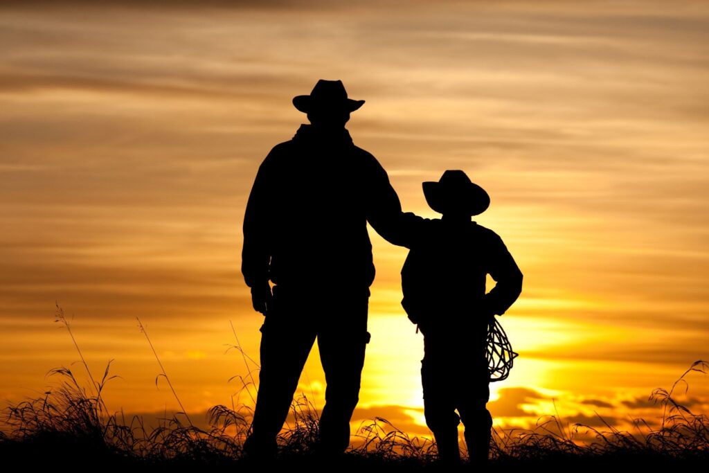 silhouette of two people wearing cowboy hats sunset