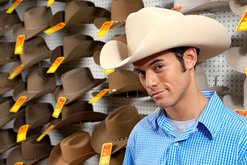 man standing in front of wall of cowboy hats for sale