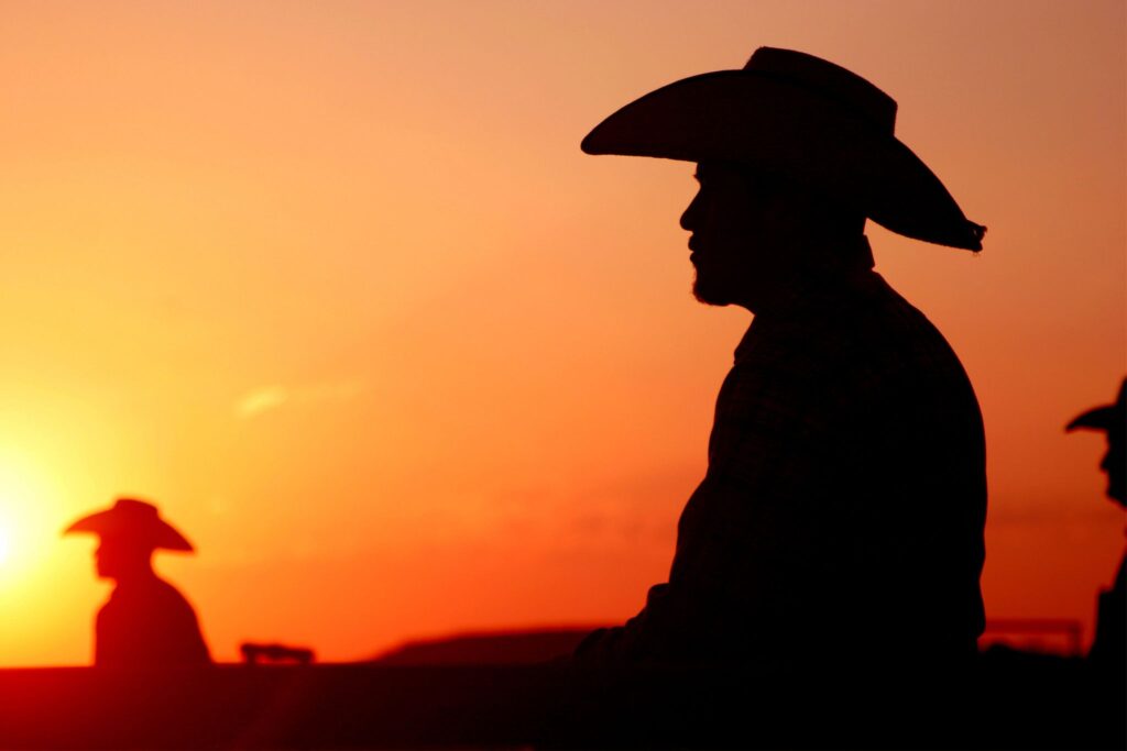 silhouette of man wearing cowboy hat at sunset