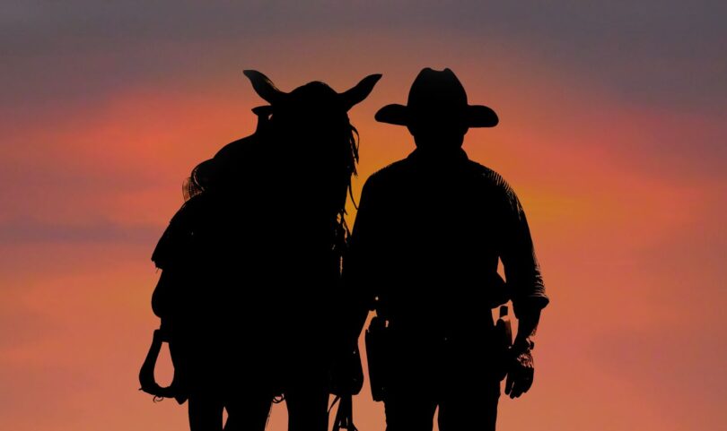silhouette of cowboy and horse at sunset