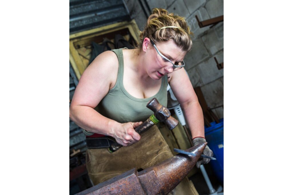 woman hammering horse shoe on anvil