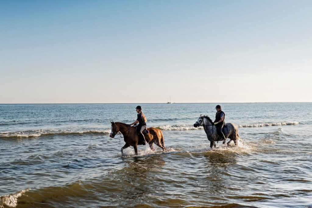 two people riding horses in the ocean