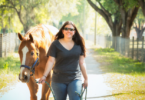 woman leading horse down road