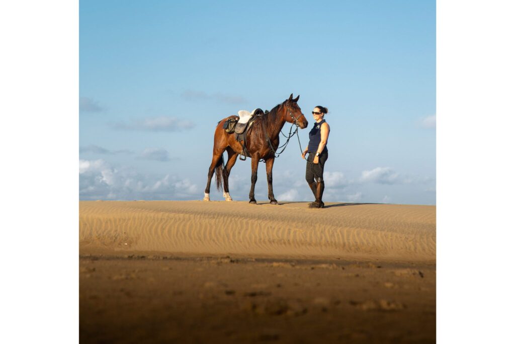 woman and horse on sand dune